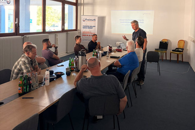 Schulungstag im TecCenter Bad Salzdetfurth: Teilnehmer am Konferenztisch, Vortrag zur Mauerwerksabdichtung