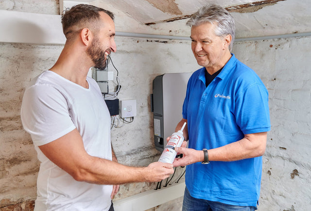 Mitarbeiter von Freimuth Bautenschutz übergibt einem Kunden im Keller eine Isofin®-Flasche